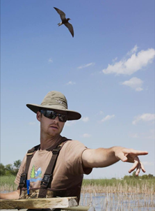 Caleb Putnam, wearing sunglasses and hat, bird overhead