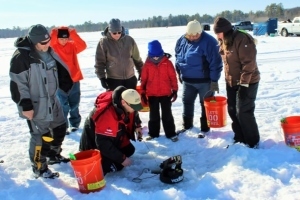 Ice fishing clinic instructor teaches students on frozen lake