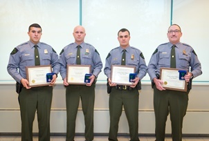 Four male conservation officers in uniform holding Lifesaving Award plaques