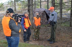 conservation officer talks to two deer hunters while being filmed for Wardens TV show