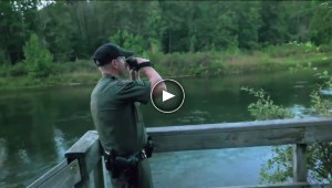 conservation officer looks over lake through binoculars in video still frame