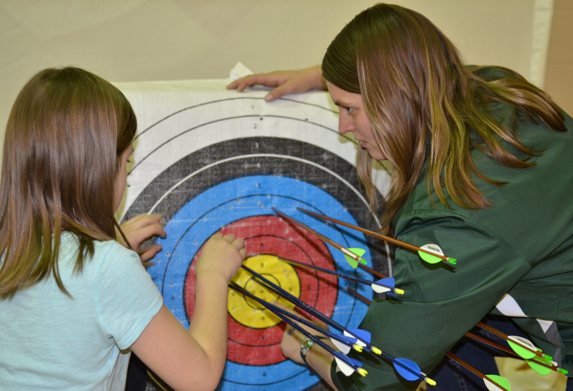 Northern Michigan University senior Casey DeVooght talks with archer Kaylee Helman as they pull their arrows at the Cherry Creek Elementary School.