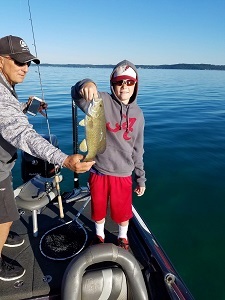 young boy holding up smallmouth bass caught on charter trip