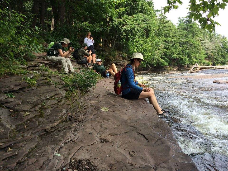 Beyond BOW hikers enjoy a break along a rushing river.