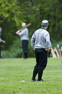 vintage base ball pitcher (in foreground) stares down batter at home plate