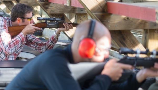 two men target shooting with rifles at shooting range