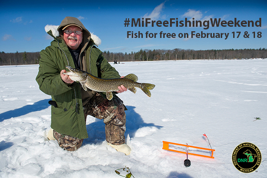 Man holding up a pike he caught while ice fishing in Michigan with words promoting Free Fishing Weekend