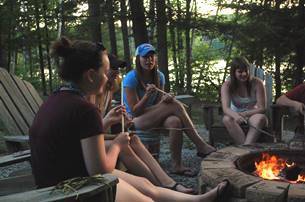 Girls around campfire in the woods