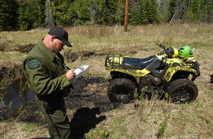 A Michigan conservation officer takes down information alongside an off-road vehicle.