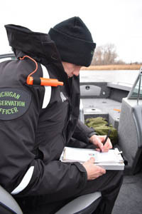 A Michigan conservation officer writes a ticket while on a boating patrol.
