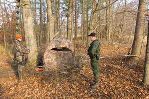 A Michigan conservation officer talks with a hunter at the base of his tree stand.