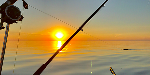 sunset on a lake with a fishing pole