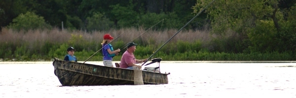 dad and kids fishing in a boat on a lake