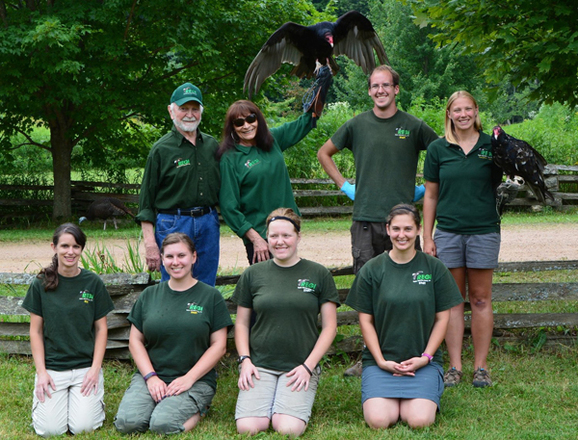 Marge Gibson, middle back row, with her husband and 2017 staff at her Raptor Education Group, Inc.