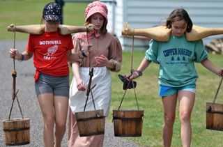 Park visitors receive instruction on how to carry water with buckets and a yoke at Fort Wilkins in Keweenaw County.