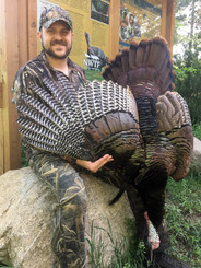 A successful hunter displays the turkey he shot at a Michigan Turkey Tract.