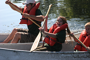 smiling kids and dad racing canoes