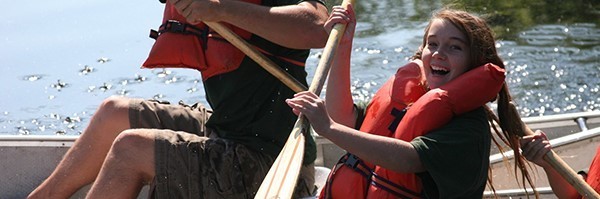 smiling girl wearing life jacket rowing a canoe