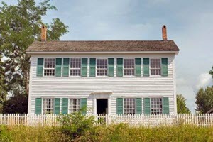 Walker Tavern, a two story white wood-framed building with green shutters, stands on a rise above US12 in Brooklyn, MI