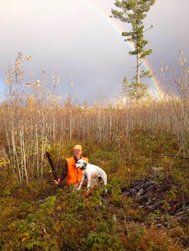 Hunter with dog and rainbow in the background