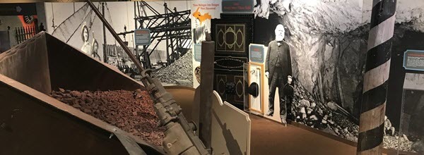 Exhibit at the museum includes a reproduction ore cart to the left, and wall-to-wall information panels on the right. 