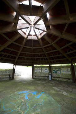 The interior of the stone memorial pavilion includes a floor map and interpretive signs on the walls.