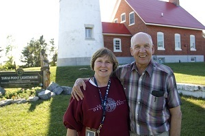 Volunteer lighthouse keepers stand in front of the Tawas Point Lighthouse