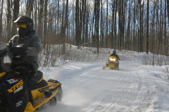 Two snowmobilers enjoy a sunny afternoon along a trail in Gogebic County.