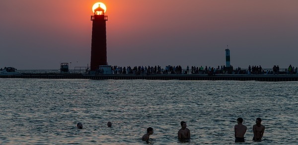 People watch a sunset and swim at a beach in Grand Haven