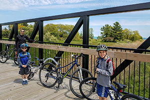 father and two sons on bikes on bridge