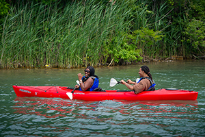 two people in kayak paddling on river
