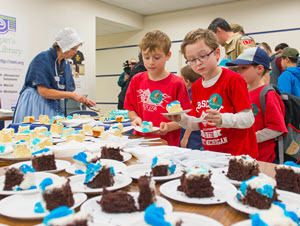 two boys pick cake from a table full of slices