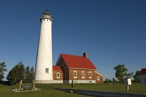 A view of the Tawas Point Lighthouse and keeper's quarters against a blue sky