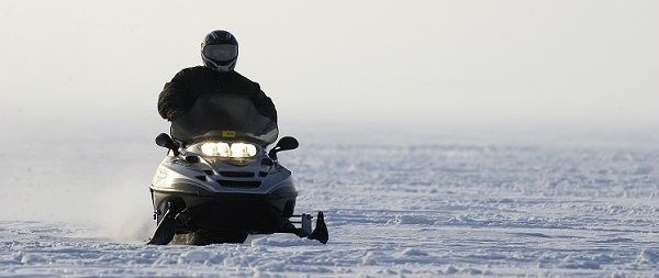 a snowmobile rider glides across the snow in Michigan