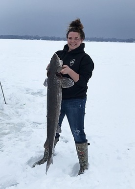 Woman holding a sturgeon, on a frozen lake