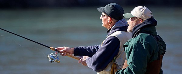 DNR instructor helping student cast while standing in river