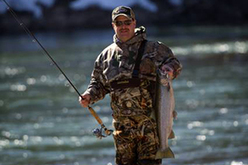 fisherman in waders holding steelhead and fishing pole