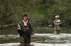 two women fly fishing in stream