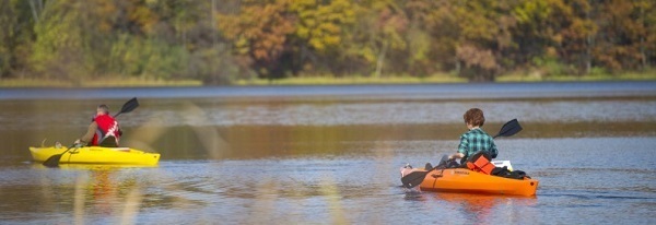 two kayakers on the water, paddling away from the camera
