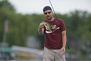 angler holding bass and fishing pole