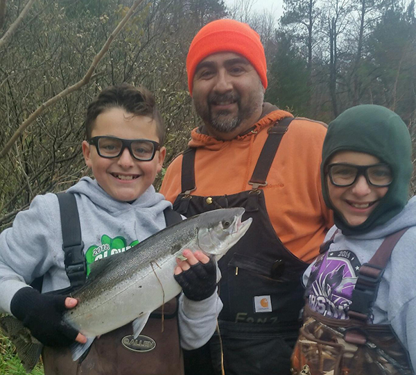 Two young boys and adult male holding up catch