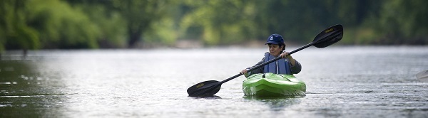 kayaker wearing a baseball cap, front view, paddling on the Muskegon River