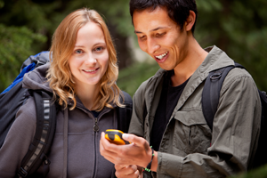 Two people looking at GPS device in the woods