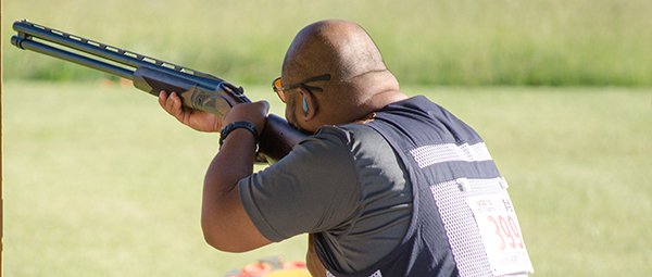 man aiming shotgun to shoot sporting clays