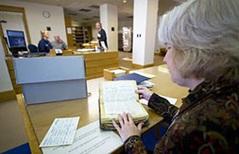 A woman looks through archival materials at a table. 