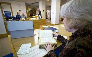 A woman looks through archival materials at a table. 