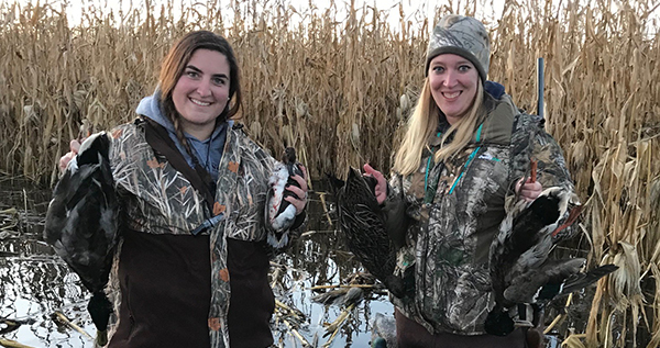 two female hunters in swamp holding ducks they took