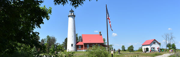View of Tawas Point lighthouse and gift shop viewed through the trees on a trail.