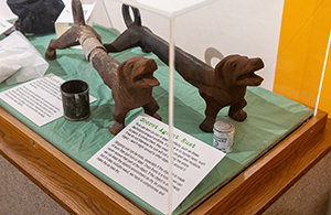 rusted dachshund-shaped andirons in display case