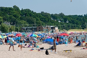 crowded beach on a sunny day at Grand Haven State Park, many umbrellas, visitors, etc.